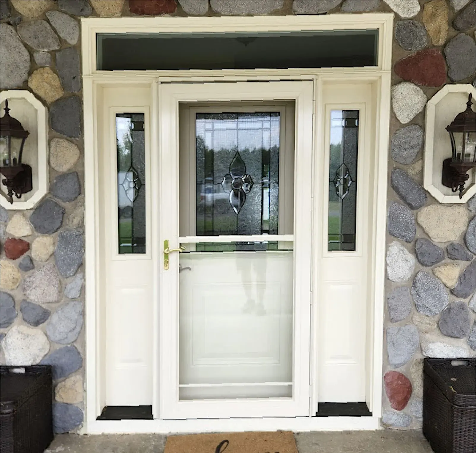 White front entry door with decorative glass and sidelights installed in a stone exterior