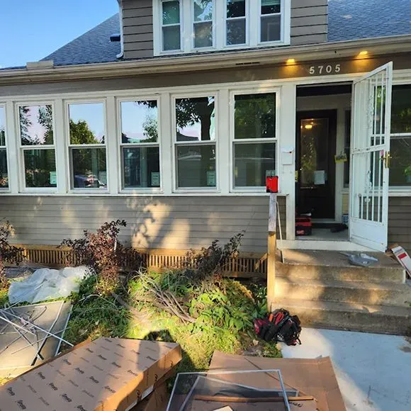Multiple white replacement windows installed across the front porch of a residential home