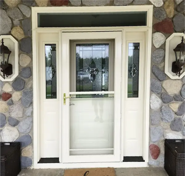 White front entry door with decorative glass and sidelights installed in a stone exterior
