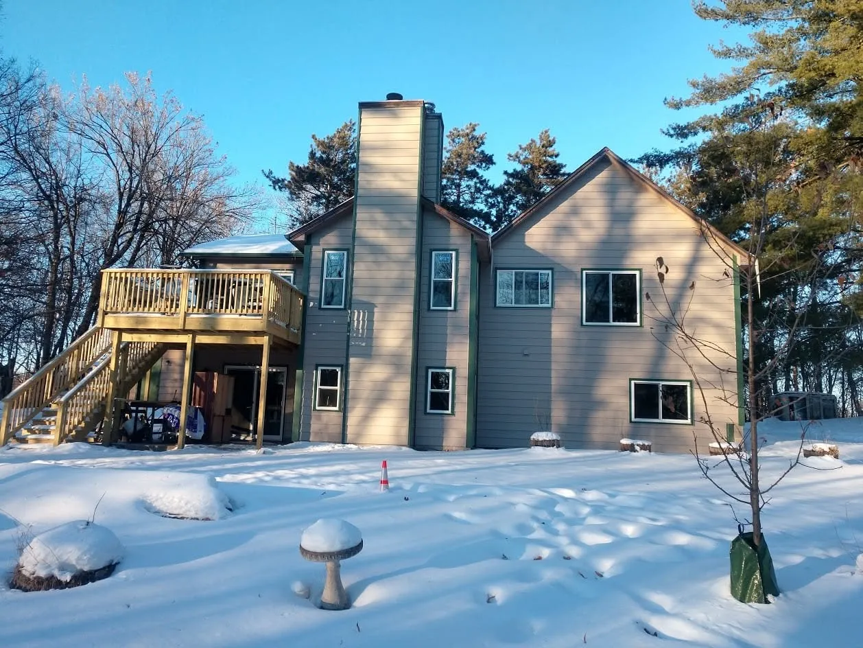 Completed full siding replacement with tan horizontal siding on a multi-story home with a rear deck