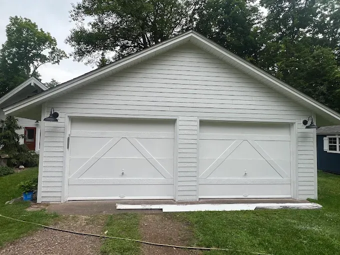 Detached garage with completed white siding replacement
